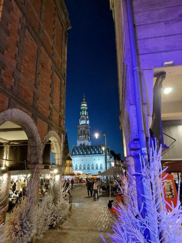 a view of a building with a clock tower at night at Entre les places, spacieux avec Parking Gratuit in Arras