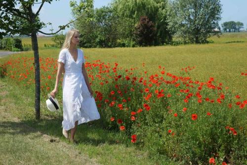 a woman walking through a field of red flowers at ChienMarin Healthfarm & Residences Anno 1712 ***** in Nieuwpoort