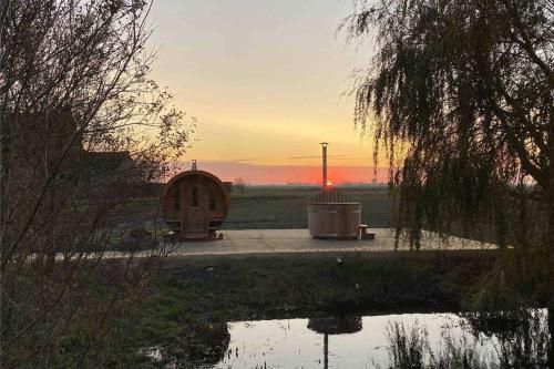 a sunset with a wooden cabin in a field at ChienMarin Healthfarm & Residences Anno 1712 ***** in Nieuwpoort