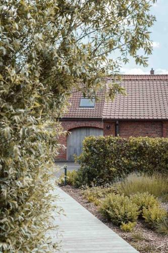 a brick house with a large door and a sidewalk at ChienMarin Healthfarm & Residences Anno 1712 ***** in Nieuwpoort