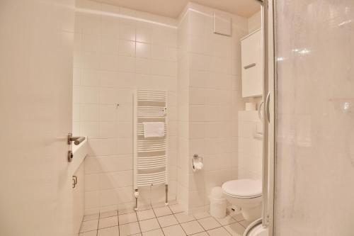 y baño blanco con aseo y ducha. en Strandduene Stranddüne Appartement 23, en Haffkrug