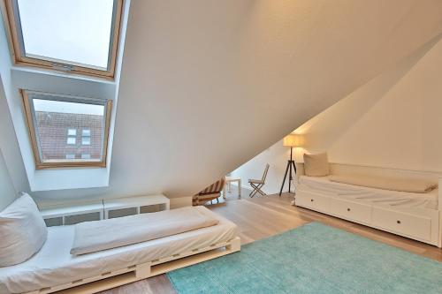 1 dormitorio en el ático con 2 camas y ventana en Strandduene Stranddüne Appartement 23, en Haffkrug