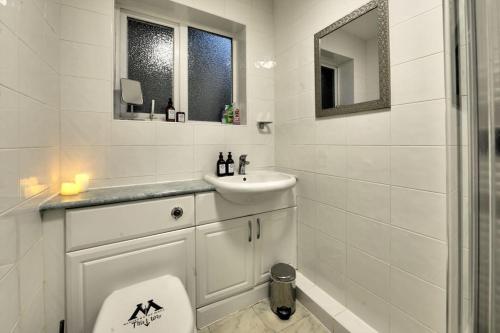 a white bathroom with a toilet and a sink at Harry's House (Muggles welcome too!) in Watford