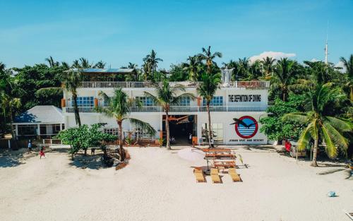 een hotel op het strand met stoelen en palmbomen bij johandive in Daanbantayan