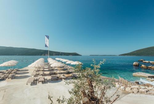 a row of chairs and umbrellas on a beach at Hotel Perla in Herceg-Novi
