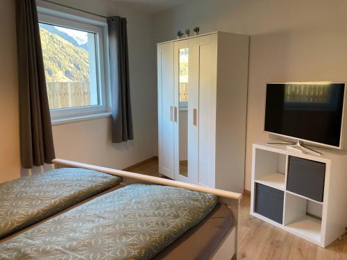 a bedroom with a bed and a tv and a window at Ferienwohnung Jasmin in Wenns