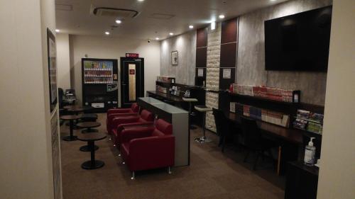 a library with a waiting room with red chairs and a tv at HEARTS Capsule Hotel & Spa Nakasu -Male only- in Fukuoka