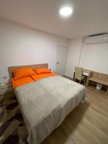 a bedroom with a bed with orange pillows and a table at Apartmani Daisy in Velika Gorica