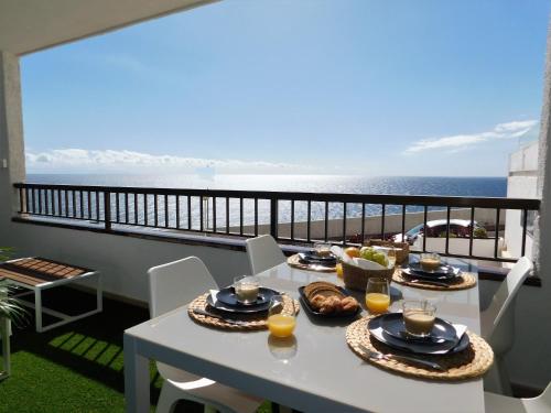 a table with food on a balcony with the ocean at Luxury Flat to the Atlantic Ocean in Radazul