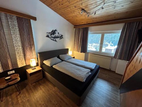 een slaapkamer met een bed en 2 ramen bij Appartements Max&Moritz in Kaunertal