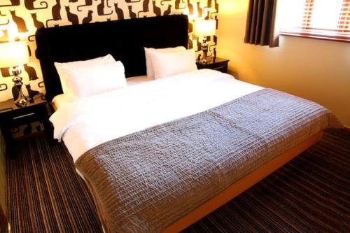a bedroom with a large bed with white sheets at Cheshire Cat in Nantwich