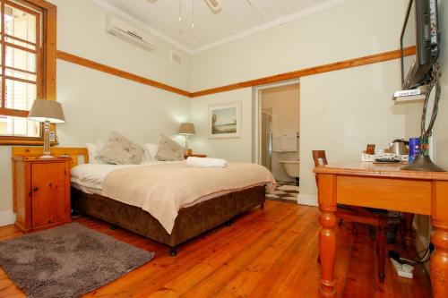 a bedroom with a bed and a desk in it at Coweys Corner in Durban