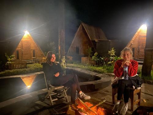 two women sitting on chairs around a fire at Triangle House and hot spring in Kintamani