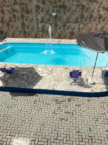 a swimming pool with two chairs and an umbrella at Pousada Canto Juquehy in Juquei