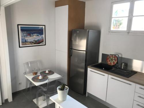 une cuisine avec un réfrigérateur en acier inoxydable et une table dans l'établissement Bel F2 près de la plage, à Ajaccio