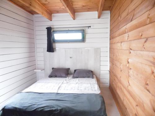 a small bedroom with a bed in a wooden wall at Chalet cosy climatisé avec parking et Internet in Doué-la-Fontaine