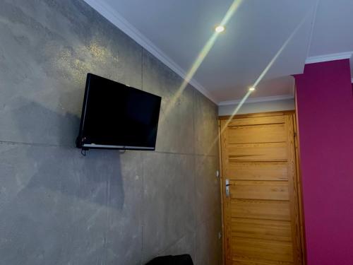 a flat screen tv on a wall next to a door at Pokoje z własnymi aneksami kuchennymi - Zbigniew Lassak in Biały Dunajec