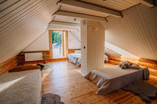 ValmiermuižaにあるBrīvdienu māja ''Rātes'' Valmiermuižaのベッド2台と窓が備わる屋根裏部屋です。