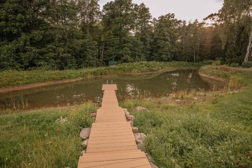 a wooden bridge over a pond in a park at Brīvdienu māja ''Rātes'' Valmiermuiža in Valmiermuiža