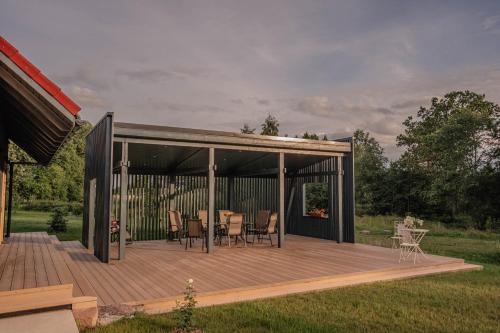 a pavilion with a table and chairs on a deck at Brīvdienu māja ''Rātes'' Valmiermuiža in Valmiermuiža