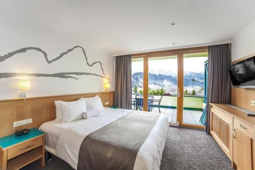 um quarto de hotel com uma cama grande e uma varanda em Alpine Club, Austria 