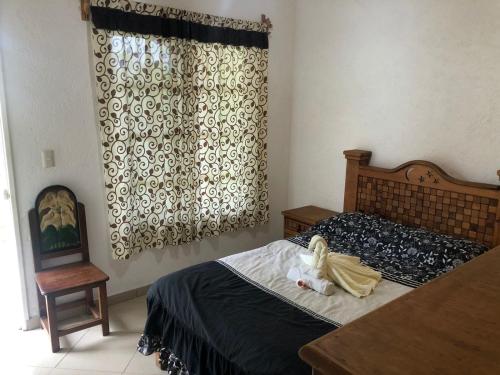 1 dormitorio con 1 cama, 1 silla y 1 ventana en Los Robles, en Tepoztlán