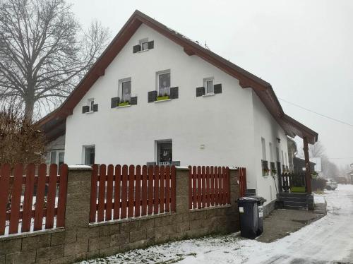 une maison blanche avec une clôture dans la neige dans l'établissement U Berňáků, à Abertamy