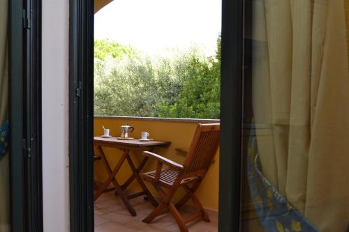 a balcony with a table and a chair and a window at Hotel Villa Del Parco in La Maddalena