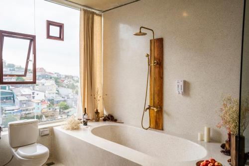 a bathroom with a tub and a toilet and a window at Cherry Suites Dalat in Da Lat