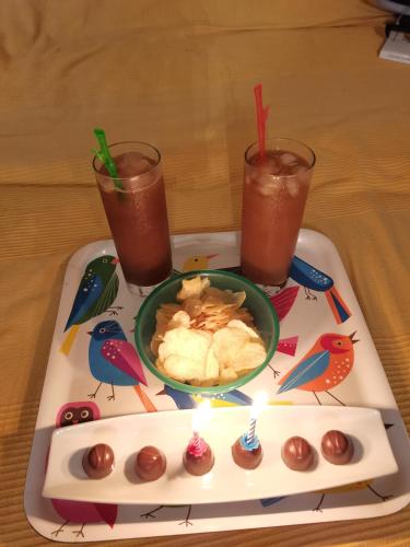 a tray with a candle and a plate of food and drinks at Gites "les colibris" in Schœlcher
