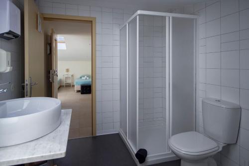 uma casa de banho com um WC, um lavatório e um chuveiro em Peniche Surfcamp Hostel no Baleal