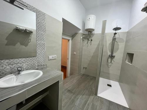 y baño con lavabo y ducha con espejo. en Pensión Bienvenido, en Sevilla