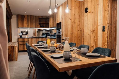 a dining room table with chairs and a wooden wall at Appartement Pixel by ExplorHome in Tignes