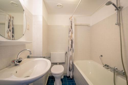 a bathroom with a sink and a toilet and a tub at Appartementen Beatrix in De Koog