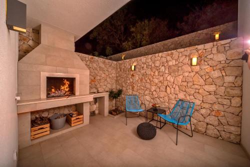 a stone wall with two chairs and a fireplace at Villa Bellevue Bast in Baška Voda