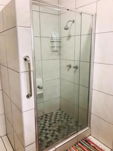 a shower with a glass door in a bathroom at LRN Brackenfell Homestay in Cape Town