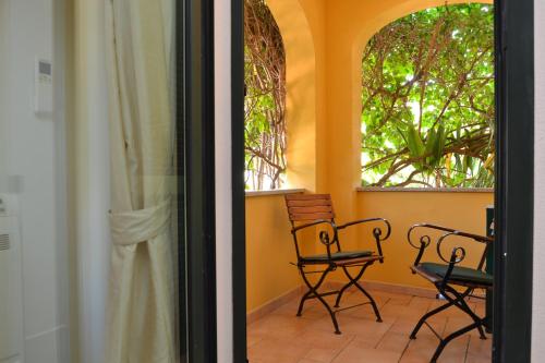 a balcony with two chairs and two windows at Hotel Villa Del Parco in La Maddalena