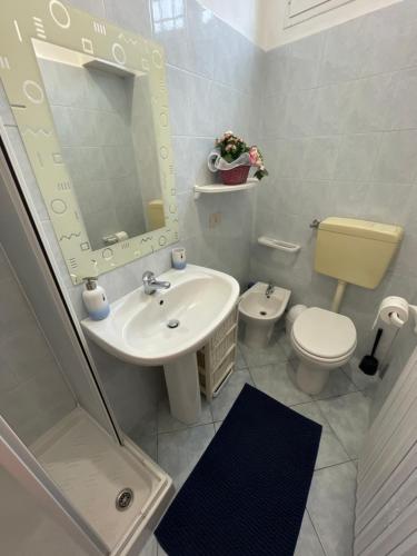 een badkamer met een wastafel, een toilet en een spiegel bij La vista sul campanile in Andorno Micca