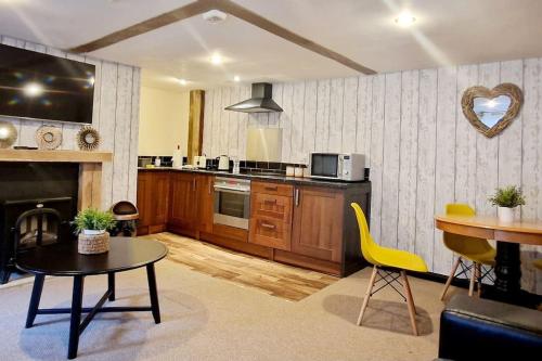 uma cozinha com uma mesa e cadeiras amarelas num quarto em The Birch Cabin with hot tub em Bristol
