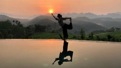 a person standing on a pool with the sunset in the background at Lua Pu Luong in Pu Luong