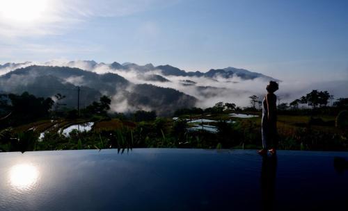 a man standing on the edge of a pool looking at the mountains at Lua Pu Luong in Pu Luong