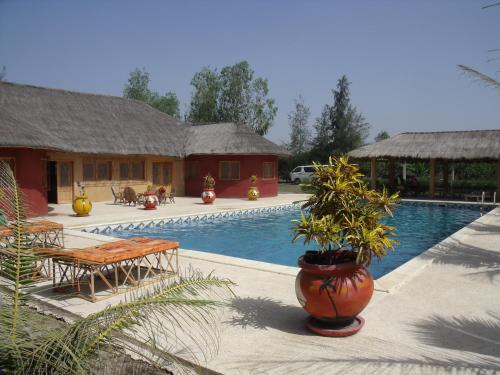 a resort with a swimming pool with tables and chairs at le baobab de nianing in Nianing