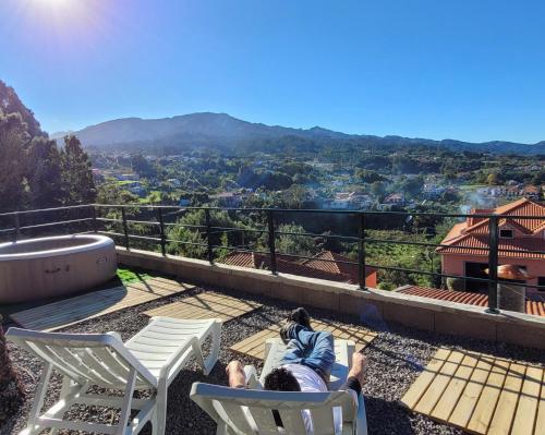 a person laying in chairs on a balcony with a view at Sleep and Go in Santana in Nature B&B in Santana