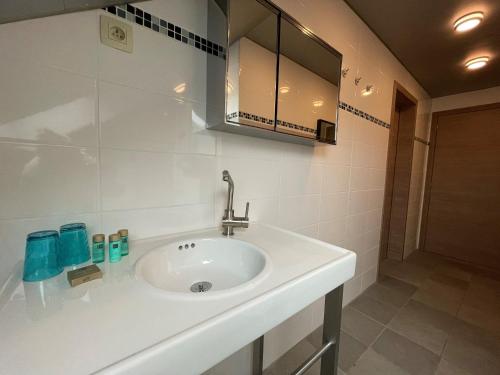 een badkamer met een witte wastafel en een spiegel bij B&B Het KoeKoeKsnest Schelle in Schelle