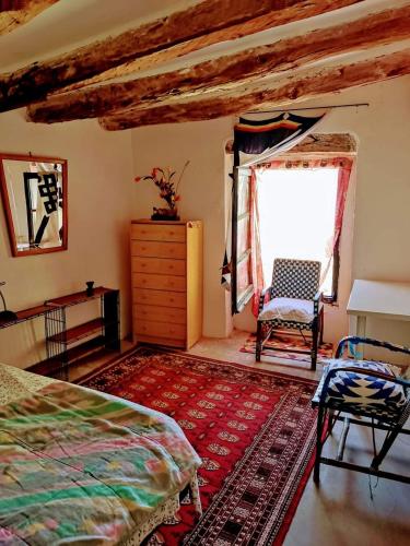 a bedroom with a bed and a window and a chair at Sidharta Room in Villalba dels Arcs