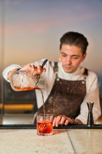 a man pouring a drink into a glass at San Antonio Summerland in Mýkonos City
