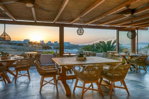 a patio with tables and chairs and the sunset at San Antonio Summerland in Mýkonos City