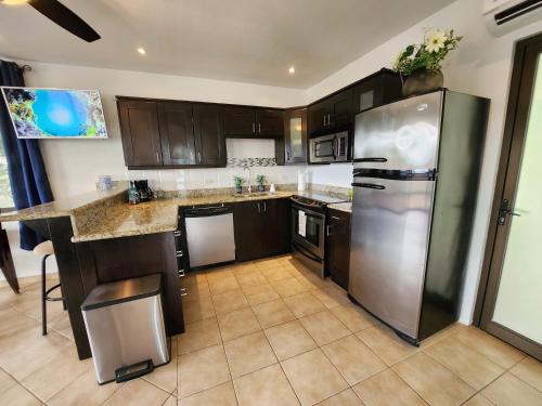a kitchen with brown cabinets and a stainless steel refrigerator at Amazing Oceanview rooftop terrace walk to beach in Coco