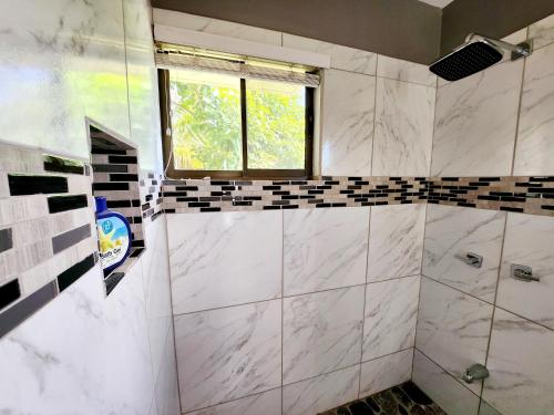 a bathroom with white marble walls and a window at Amazing Oceanview rooftop terrace walk to beach in Coco