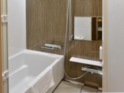 a bathroom with a tub and a sink and a mirror at Gardenvilla Shirahama in Shimoda